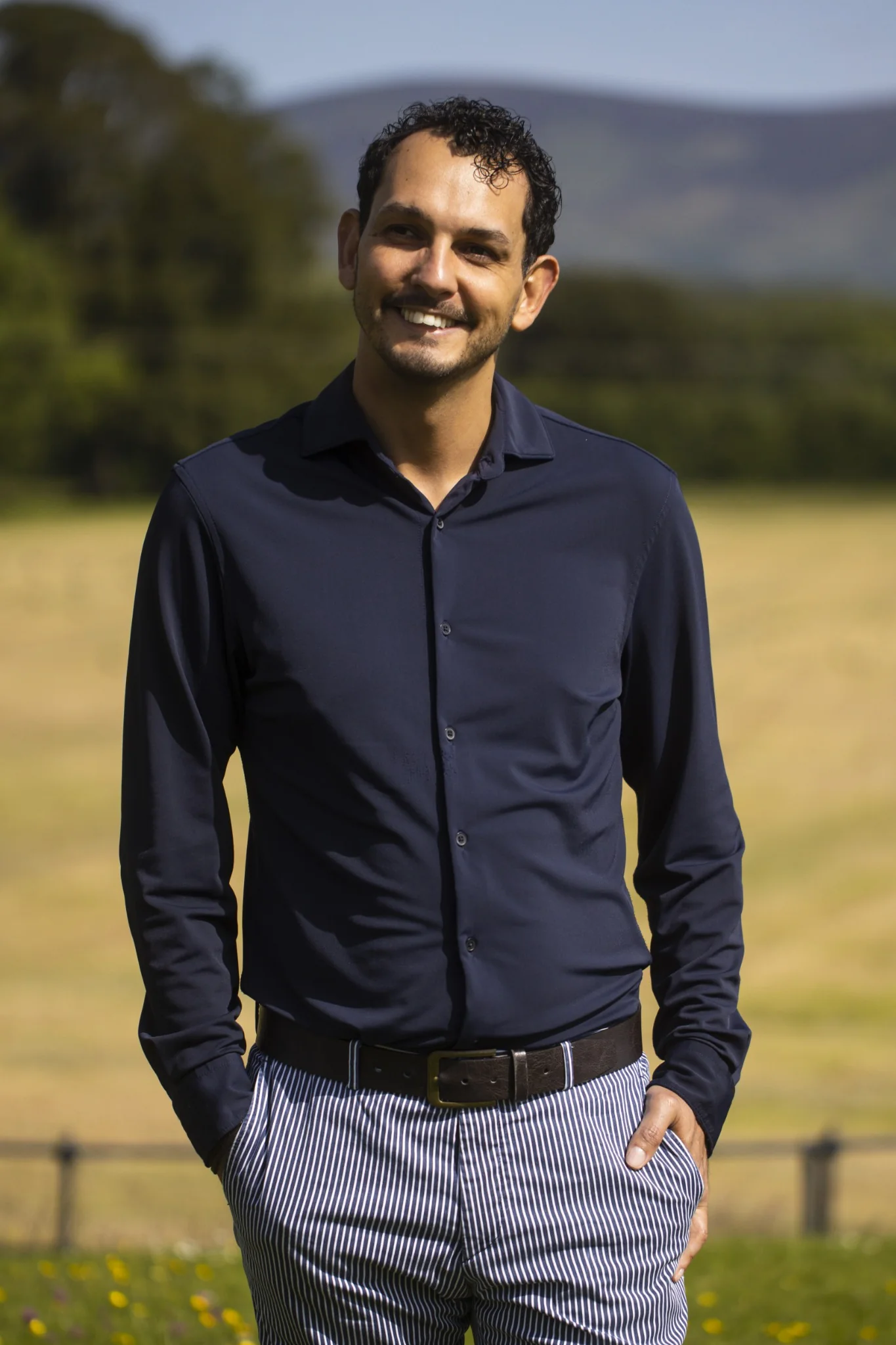 Daniel standing outdoors in a navy shirt and striped trousers